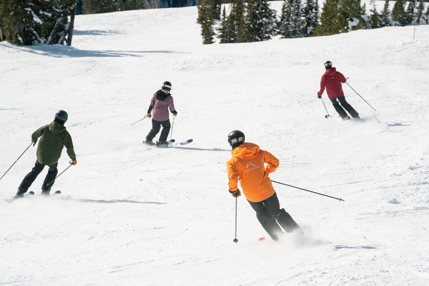 Four skiers skiing down a slope