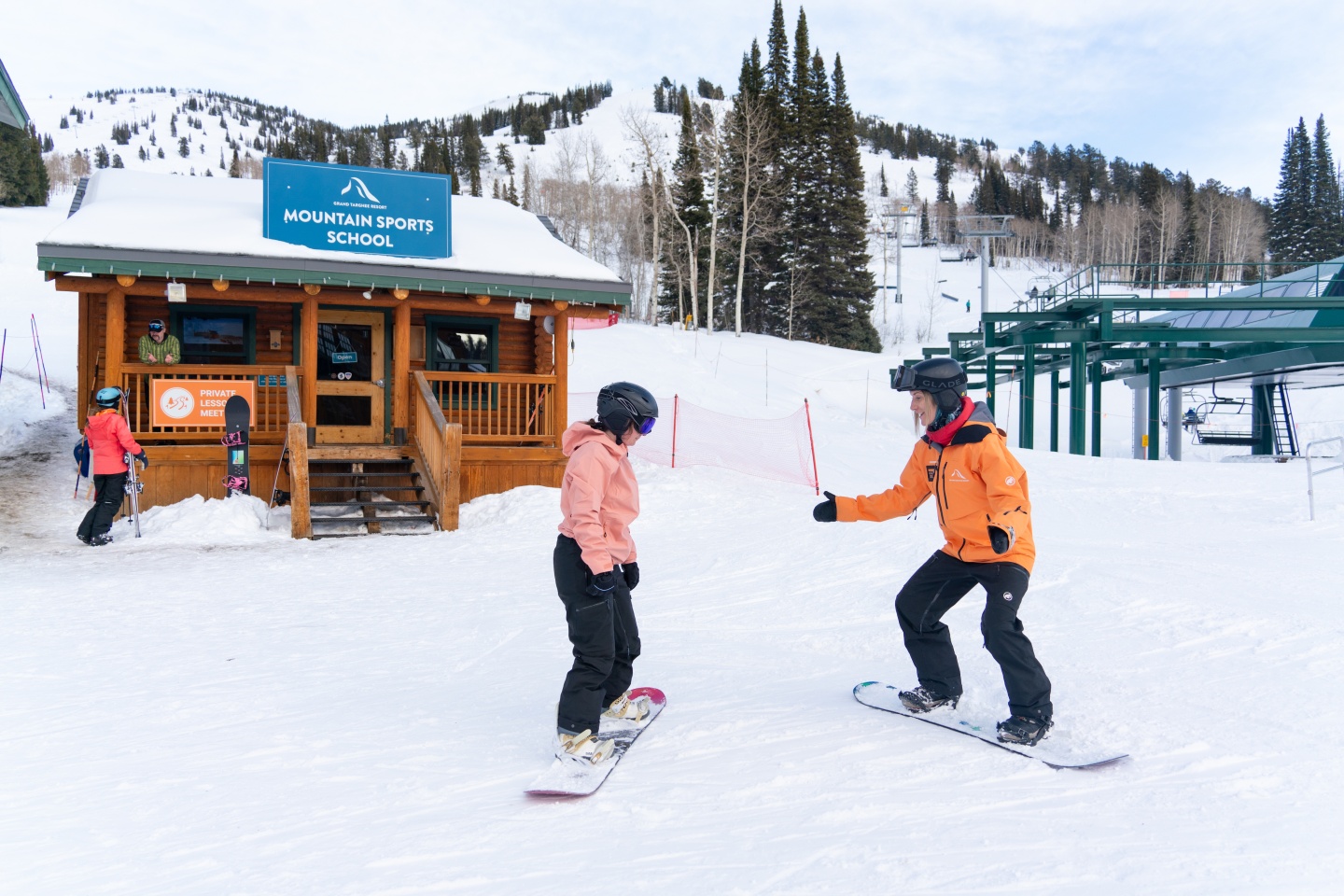 Beginner Snowboarder and Instructor outside Ski School Building