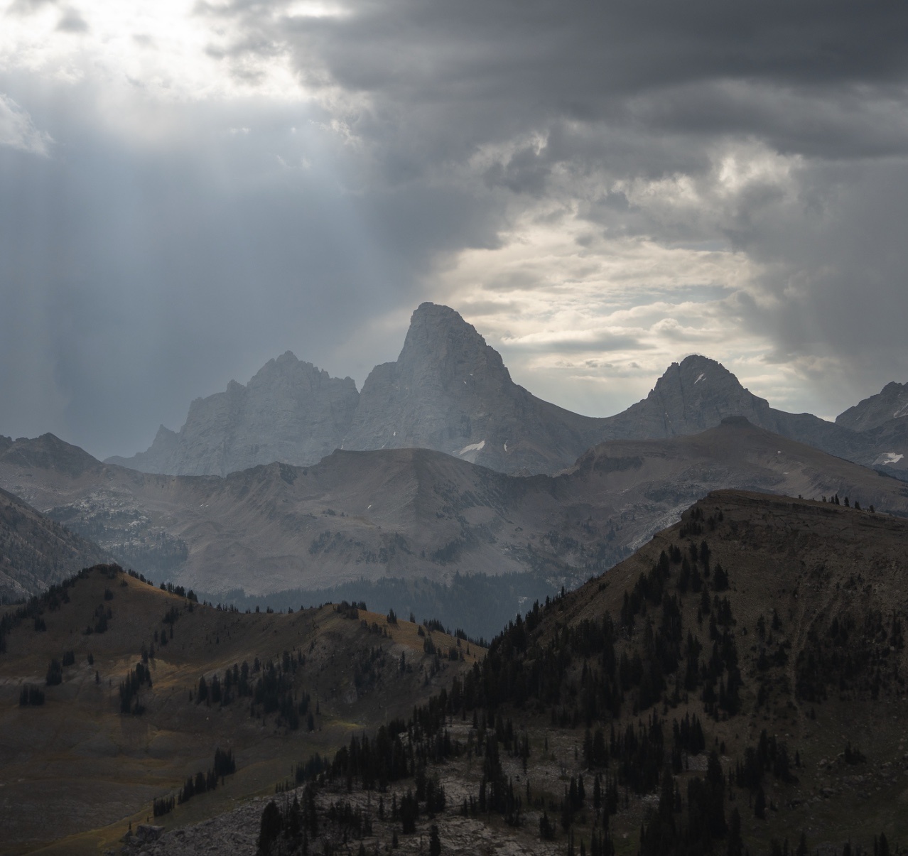 Cloudy mountain landscape with light rays shining through.