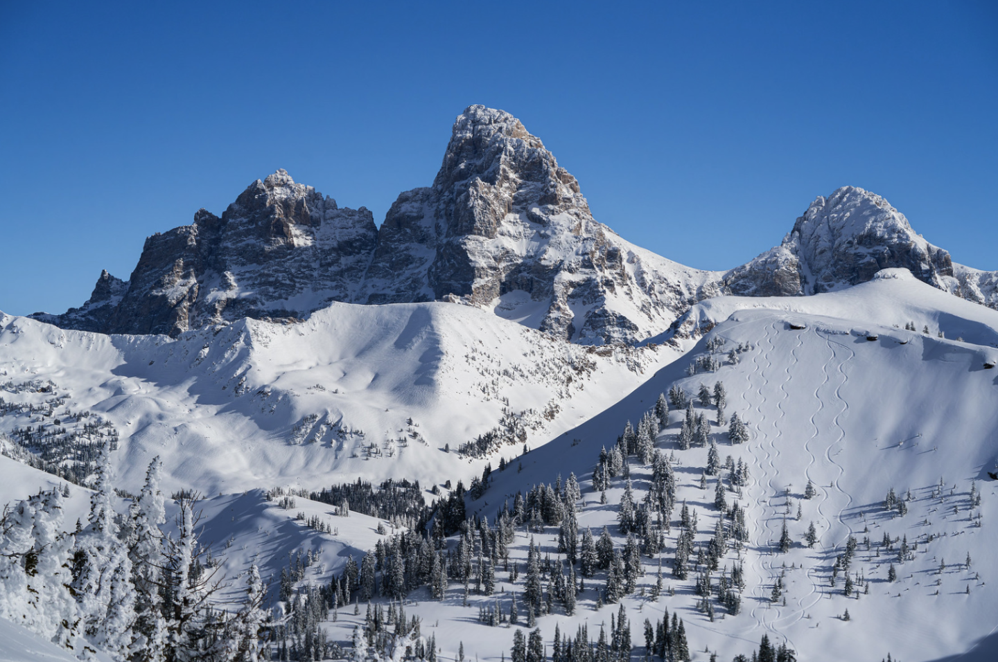 Snow-covered mountains under clear blue sky.
