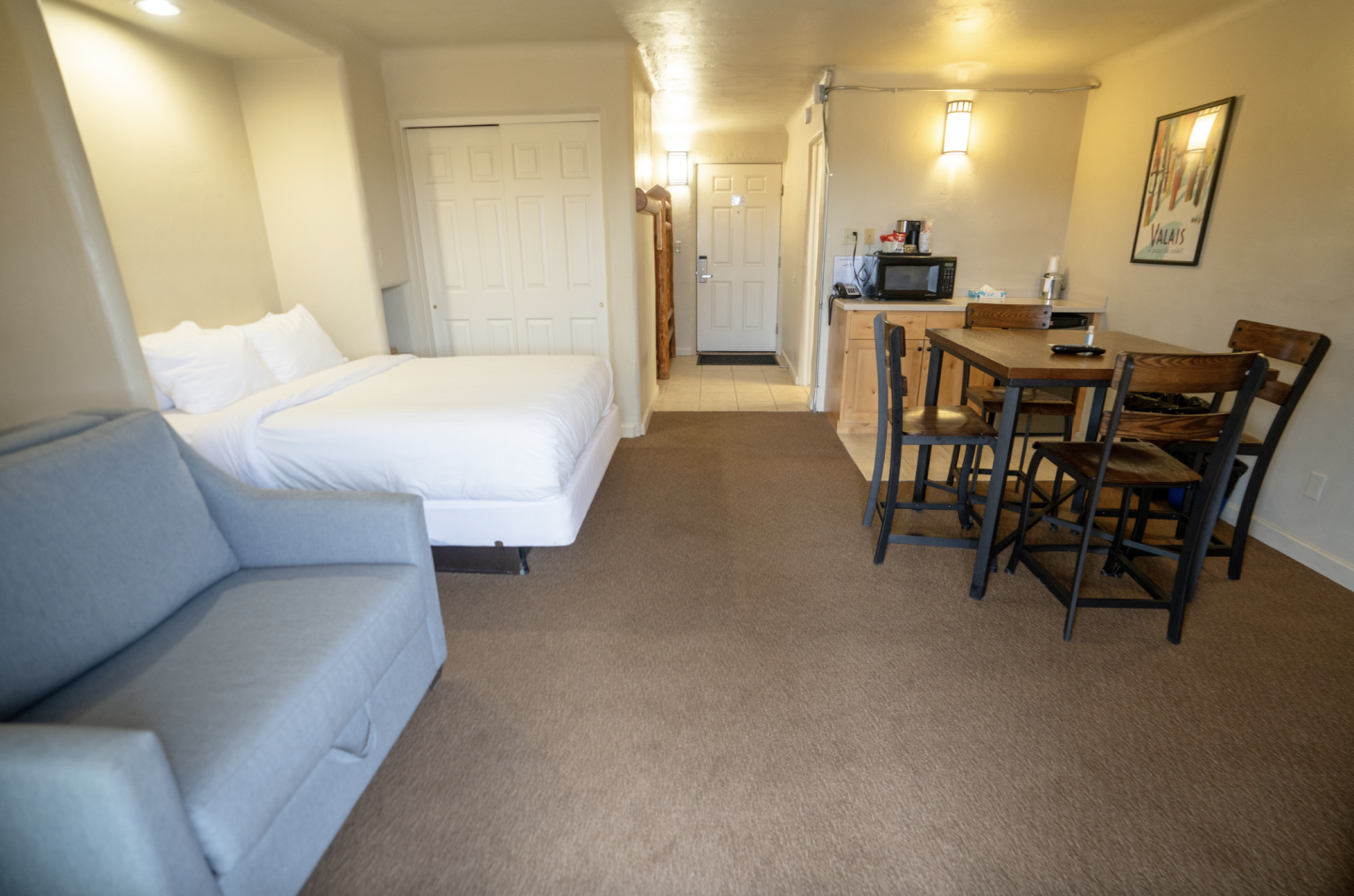 Cozy studio apartment with a bed, sofa, and dining area.