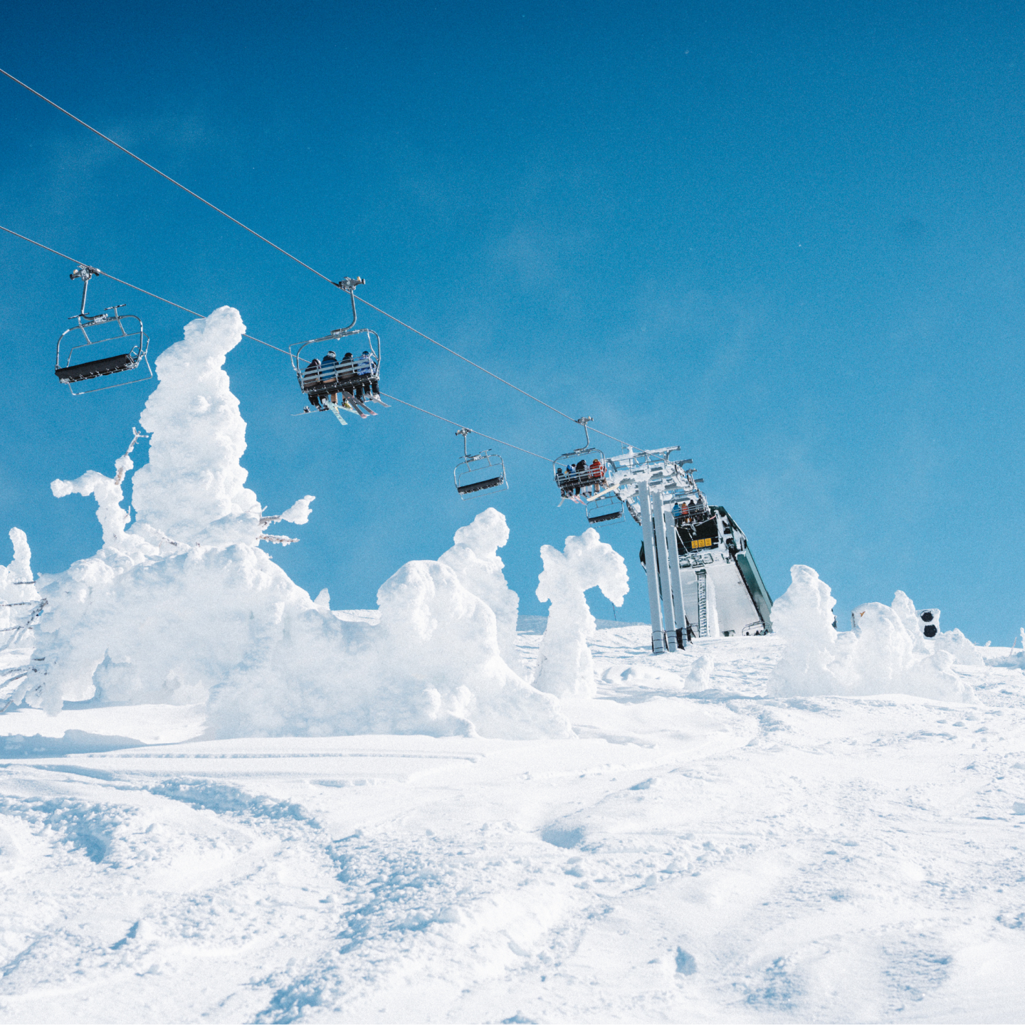 Ski lift over snowy landscape with blue sky.