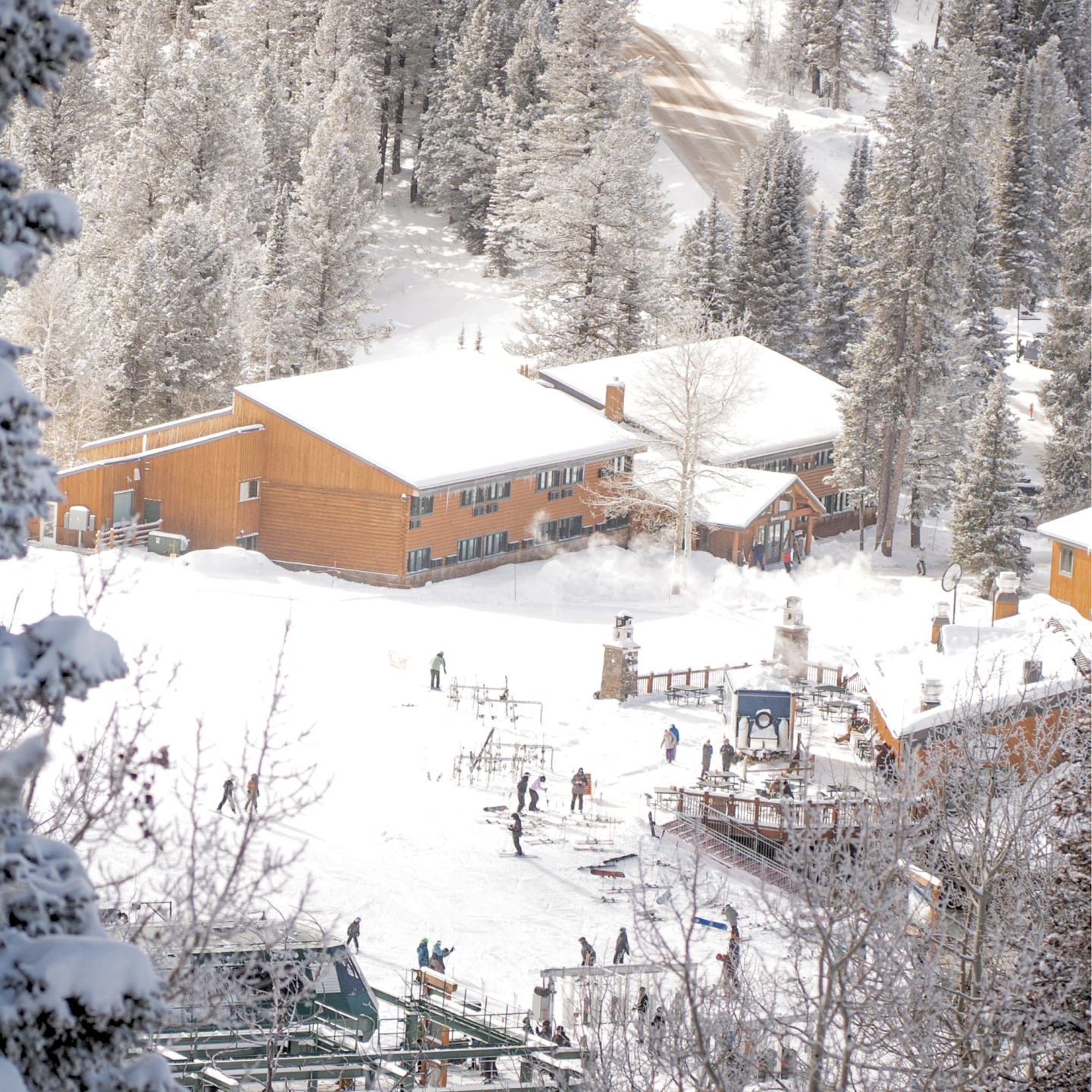 Snowy mountain lodge with skiers and snow-dusted trees.